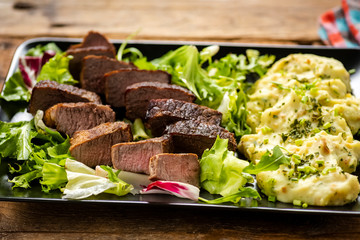 Pieces of meat on lettuce with mashed potatoes