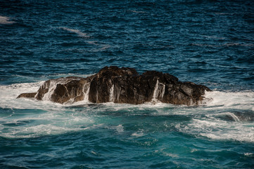 Fototapeta premium Raging sea with white waves around the rock