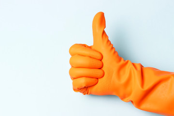 Female hand in orange rubber gloves with raised up his thumb on a white background