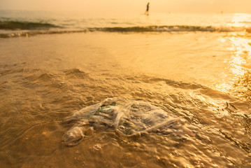 Plastic bag on the beach with sea waves at morning sunrise.Thailand.