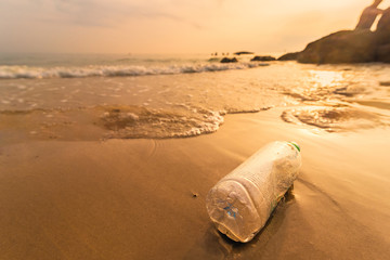 Obraz premium Empty plastic bottle on the beach with sea waves at morning sunrise.Thailand.