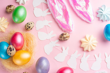 Fototapeta na wymiar Easter holiday background. Easter eggs colored with rabbit ears on a pink background with sweets. Flat lay, horizontal composition. Greeting card concept