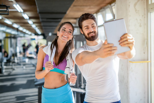 Picture of happy sporty couple taking a photo of them self in a gym.