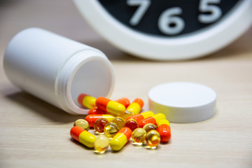 White bottle drug capsule On the desk The clock is placed beside