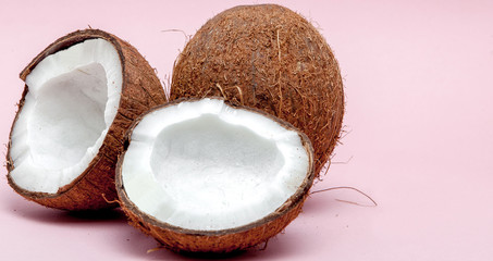 Coconut on a pink background. Minimal style. Two halves of coconut