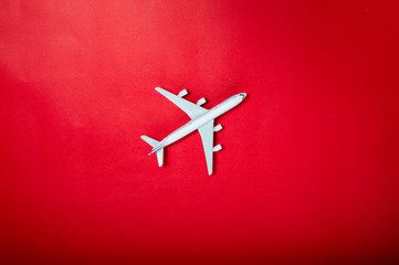 Miniature toy airplane on red background. Trip by airplane.