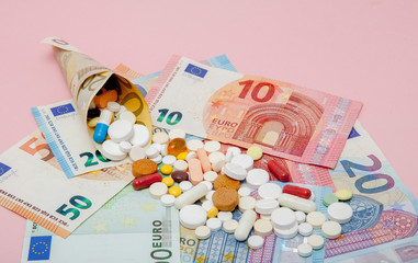 The tablets wrapped in euro with euro banknotes on a pink background. Medical concept