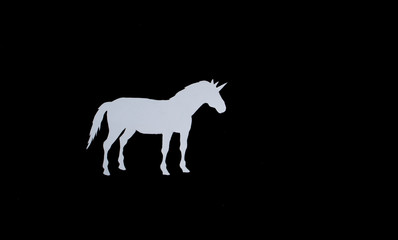 Fototapeta na wymiar White unicorn with paper on a black background