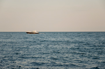 Black Sea. Water with no waves and little boat far away. Calm. Mainly cloudy weather. Blue and grey color. Before rain