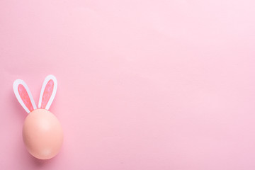 Easter holiday background. Pink Easter egg with ears on a pink background, horizontal composition. Greeting card concept