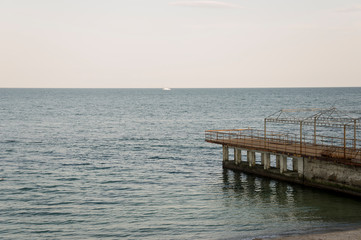 Black Sea. Water with no waves and little boat far away. Calm. Mainly cloudy weather. Blue and grey color. Before rain