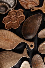 A variety of handmade DIY wooden kitchenware bowls, chopping boards, wooden trays from valuable timber on black background