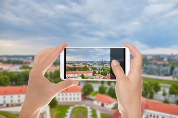 A tourist is making a photo of Aerial panoramic view of the capital of Lithuania - Vilnius on a mobile phone