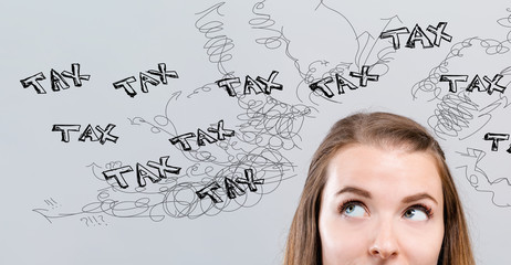 Tax problem theme with young woman looking upwards on a gray background