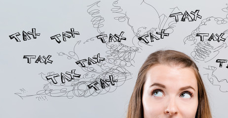 Fototapeta premium Tax problem theme with young woman looking upwards on a gray background