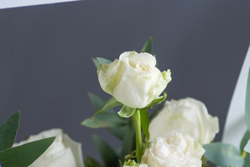 white roses in white paper box on table and gray background. Close up