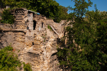 Old ancient destroyed stone house on the yard with trees around. Poverty and misery, South, summer 