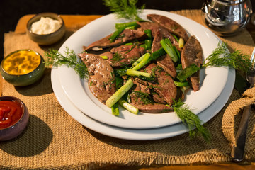 lamb liver food with green vegetables in the plate and local bread on the wooden table for restaurant and kitchen concept.