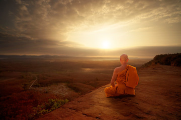 Buddhist monk in meditation at beautiful sunset or sunrise background on high mountain - obrazy, fototapety, plakaty