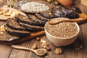 Whole grain, whole loaf and sliced pieces of multigrain bread contains whole grains ( poppy, millet, flaxseed, pumpkin seeds, and sunflower seeds) isolated on dark wooden table .