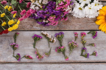 Romantic bright word love from flowers on wood. Top view, flat lay.
