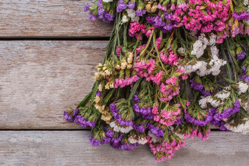 Colorful statice flowers. Wooden desk background.