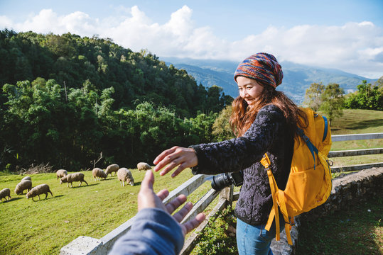 couple asians travel nature in the holiday. Hold hands running happy enjoy nature on the mountain at sheep farm Doi Pha Tang in Thailand