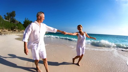 Retired Caucasian couple dancing on beach outdoor Bahamas
