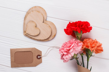 Decorative heart shaped wood, tag and colorful flowers. Flat lay. White wood background.