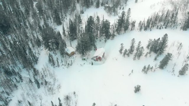 Aerial Drone Footage View: Flight over small house in the beautiful mountains in winter, 4K. Small hiking shelter in Ural Mountains, Russia. Drone flight over wooden cottage cold weather.