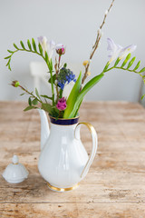 White and gold porcelain coffee pot with roses and hyacinths on a wooden tabletop. Close shot