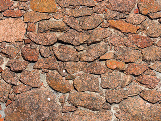 Old red granite stone texture. Ancient masonry background, close-up. Wall of the medieval city, castle retro background, sunlight