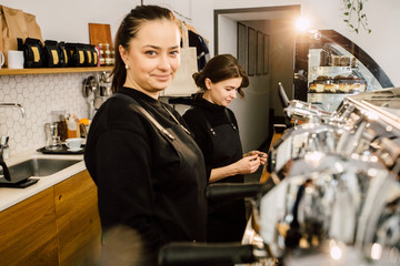 Two female baristas preparing coffee at coffee-shop. Team work and coworkers concept.