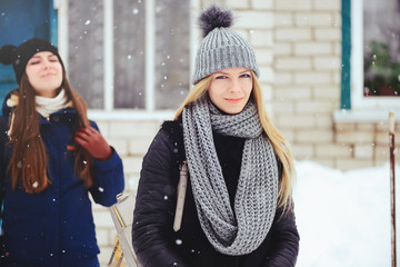 two beautiful girlfriends walk in the winter, a lot of snow and winter clothes. blonde and brunette emotions