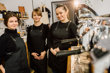 Team female baristas coworkers standing in workplace at coffee-shop. Team work and coworkers concept.