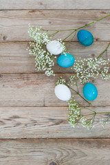 Delicate adorable spring flowers with Easter bright eggs on a wooden tabletop. Space for text