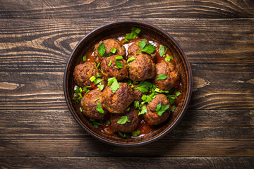Meatballs in tomato sauce on wooden table top view. 