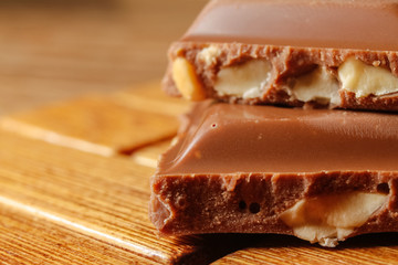 Chocolate with hazelnuts on wooden background. Macro photography.