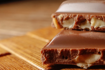 Chocolate with hazelnuts on wooden background. Macro photography.
