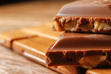 Chocolate with hazelnuts on wooden background. Macro photography.