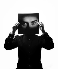 Black and white photo of man in the black shirt holding a photo with the face of a man in place of his face