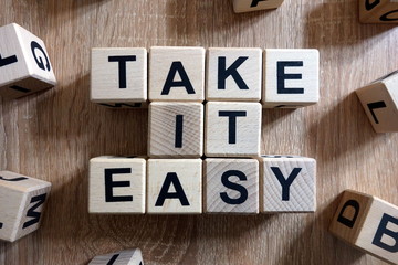 Take it easy text from wooden blocks on desk - obrazy, fototapety, plakaty