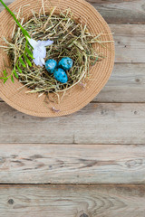 Nest in a wicker hat and painted spotted Easter eggs with flower. In the top left corner. Empty text space