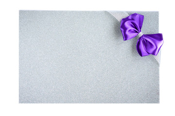 Purple bow with silver ribbon on purple glitter background. Festive background.
