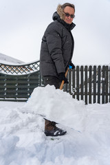 Mann räumt Schnee auf dem Fußweg vor der der Einfahrt