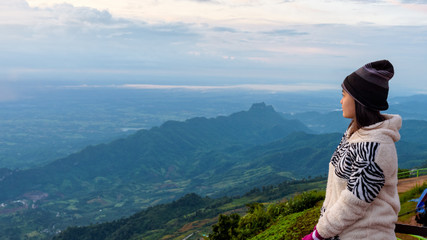 Naklejka premium Woman tourist in a sweater dress watching the beautiful nature landscape of the forest and mountain during the sunrise at Phu Thap Boek Viewpoint Phetchabun, Thailand, 16:9 widescreen