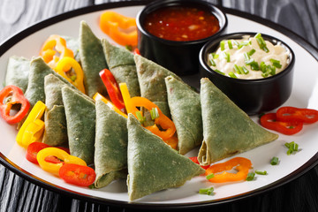 Indian spinach samosa with vegetables and sauces close-up on a plate. horizontal