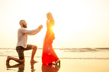 Romantic marriage proposal at the seaside at sunset on the beach sea. Young couple in love female said yes to offer of marriage February 14, St. Valentine's Day - obrazy, fototapety, plakaty