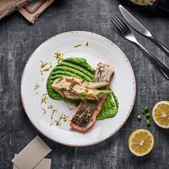 Baked salmon steak with mashed green peas , caramelized onions and lemon