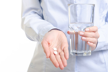 White pills and glass of water medicine in woman hand on white background, pharmacy concept